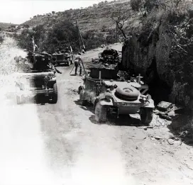 Allied jeeps pass burned out German vehicles 28-July-1943